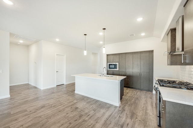 kitchen with sink, light hardwood / wood-style flooring, stainless steel gas range oven, built in microwave, and decorative light fixtures