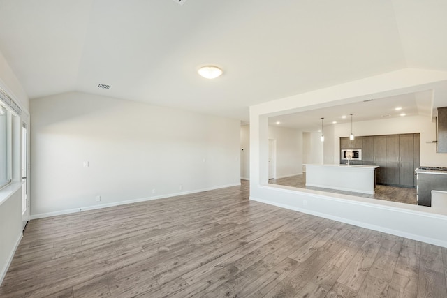 unfurnished living room with vaulted ceiling and light hardwood / wood-style flooring