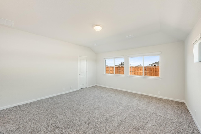 spare room with lofted ceiling, carpet, and plenty of natural light