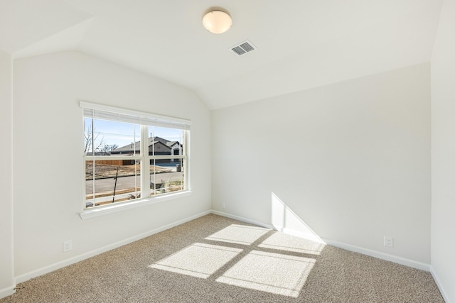 carpeted empty room featuring vaulted ceiling