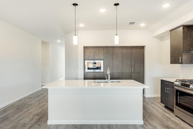 kitchen featuring sink, a kitchen island with sink, hanging light fixtures, and stainless steel gas stove