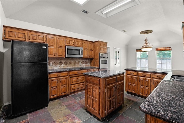 kitchen featuring backsplash, black appliances, a kitchen island, decorative light fixtures, and vaulted ceiling