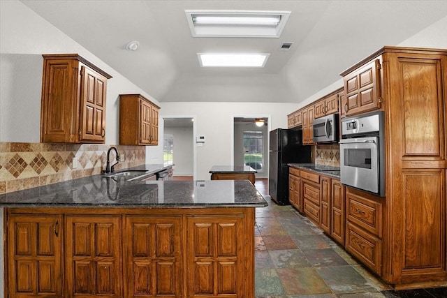 kitchen with lofted ceiling, sink, appliances with stainless steel finishes, kitchen peninsula, and backsplash