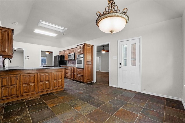 kitchen featuring appliances with stainless steel finishes, lofted ceiling, sink, ceiling fan, and kitchen peninsula