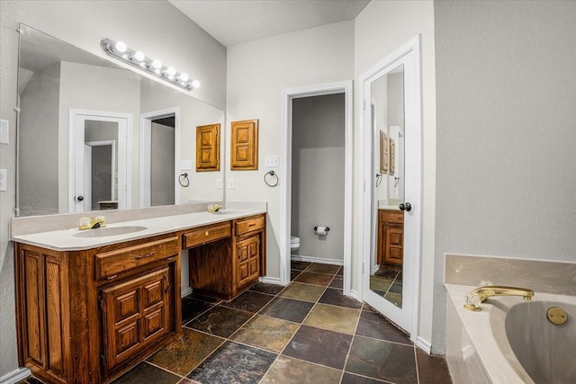 bathroom with vanity, a bathtub, and toilet