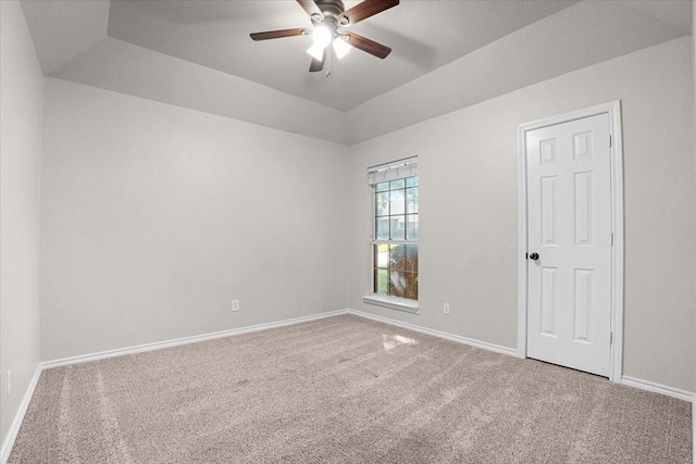 spare room with vaulted ceiling, carpet flooring, ceiling fan, and a tray ceiling