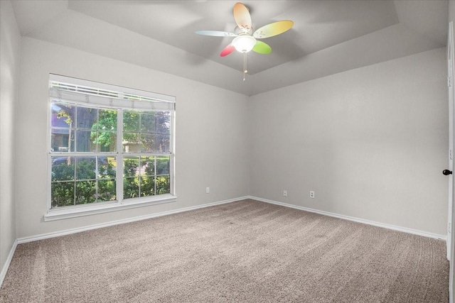 carpeted empty room featuring ceiling fan and a raised ceiling