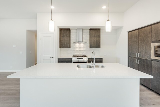 kitchen featuring hanging light fixtures, sink, light hardwood / wood-style flooring, and an island with sink