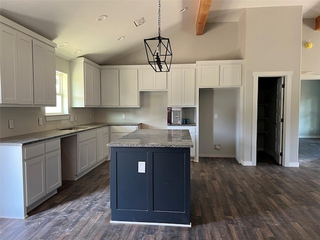 kitchen with a kitchen island, pendant lighting, white cabinets, and light stone counters