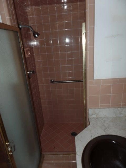 bathroom featuring a shower with door and toilet