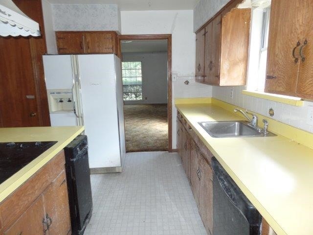 kitchen with light tile patterned flooring, sink, and black appliances