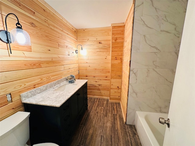 full bathroom with wooden walls,  shower combination, toilet, vanity, and hardwood / wood-style flooring