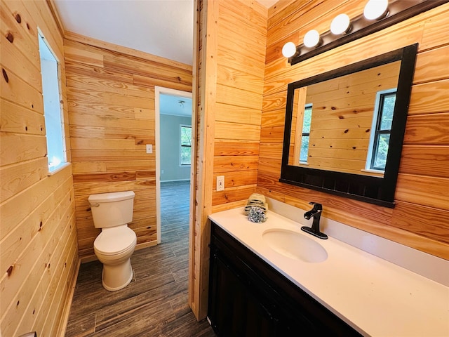 bathroom with vanity, wooden walls, hardwood / wood-style flooring, and toilet