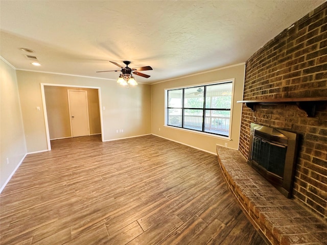 unfurnished living room with wood-type flooring, a fireplace, crown molding, and ceiling fan