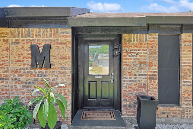 view of exterior entry featuring brick siding