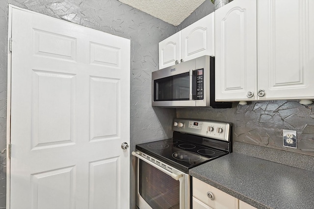 kitchen with a textured ceiling, stainless steel appliances, and white cabinetry