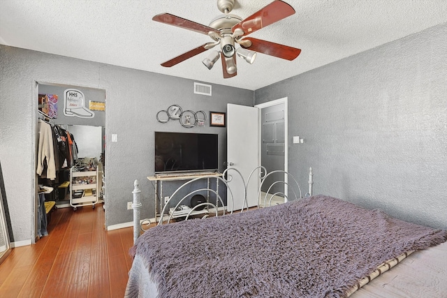 bedroom featuring ceiling fan, dark hardwood / wood-style floors, and a textured ceiling