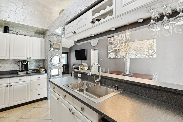 kitchen featuring white cabinetry, sink, light tile patterned floors, and decorative backsplash