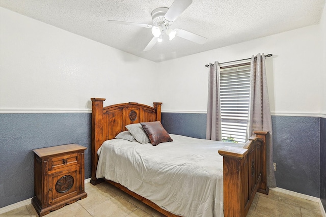 bedroom featuring ceiling fan, light tile patterned floors, and a textured ceiling