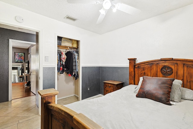 tiled bedroom featuring a textured ceiling, ceiling fan, and a closet