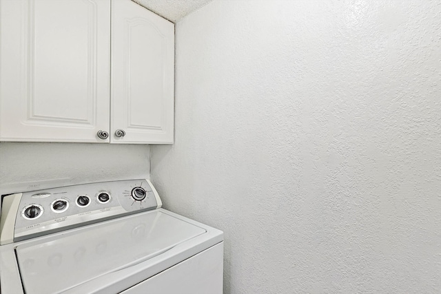 laundry area with cabinets, a textured ceiling, and washer / dryer