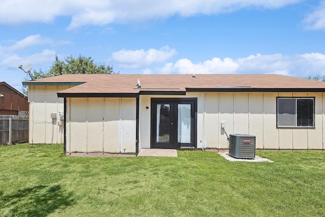 back of property with a lawn, central AC, and french doors