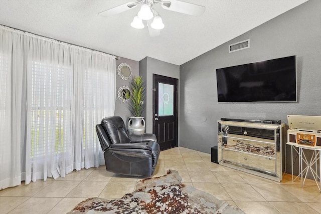 living room featuring ceiling fan, a textured ceiling, lofted ceiling, and light tile patterned flooring