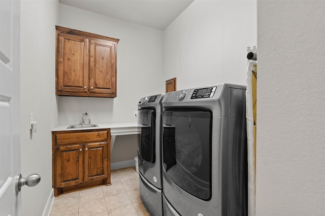 washroom featuring washing machine and dryer, sink, light tile patterned floors, and cabinets