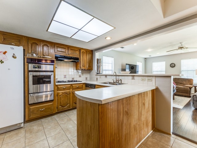 kitchen with backsplash, appliances with stainless steel finishes, sink, kitchen peninsula, and ceiling fan