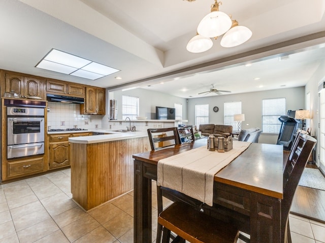 kitchen featuring a healthy amount of sunlight, kitchen peninsula, ceiling fan, and stainless steel oven