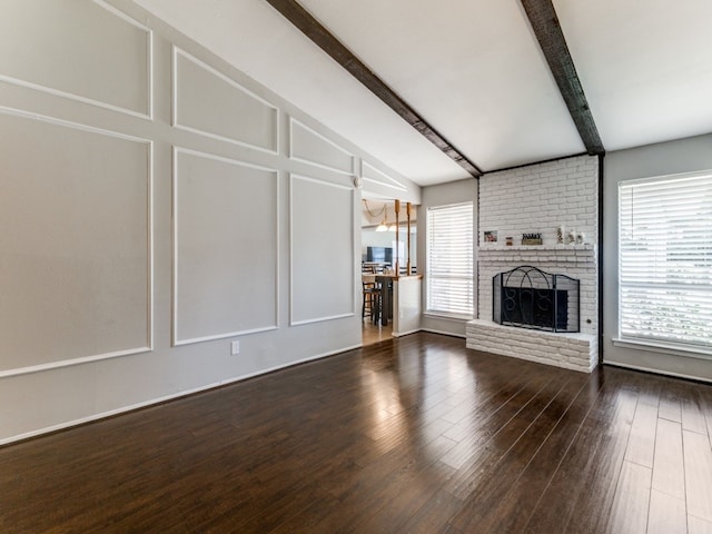 unfurnished living room with lofted ceiling with beams, dark hardwood / wood-style flooring, and a brick fireplace