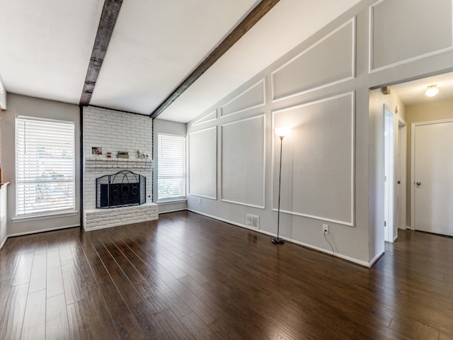 unfurnished living room featuring dark hardwood / wood-style floors, lofted ceiling with beams, and a brick fireplace