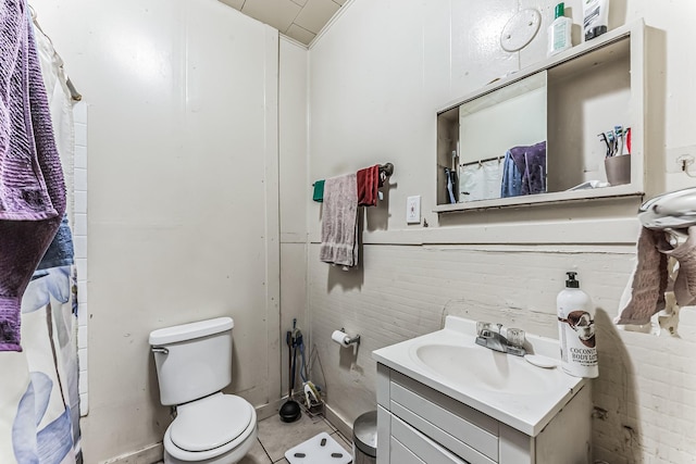 bathroom featuring vanity, wooden walls, and toilet