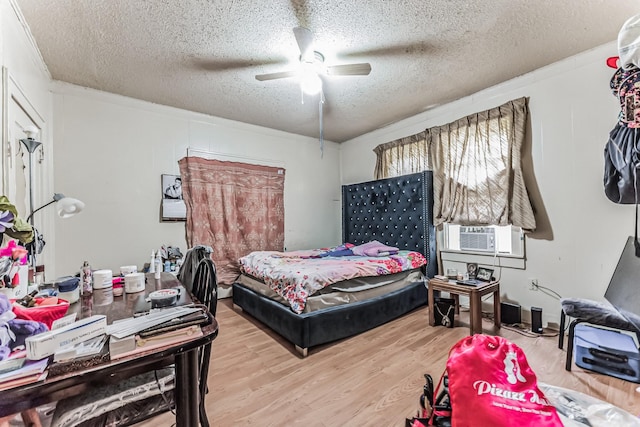 bedroom featuring cooling unit, ceiling fan, wood-type flooring, and a textured ceiling