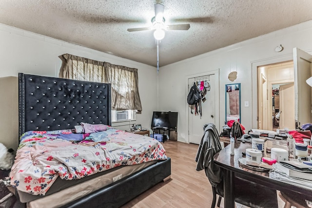 bedroom with cooling unit, ceiling fan, a textured ceiling, and light wood-type flooring