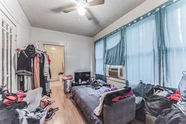 bedroom with ceiling fan, cooling unit, a textured ceiling, and light wood-type flooring