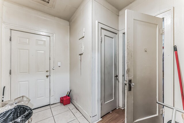 foyer with light tile patterned floors and ornamental molding