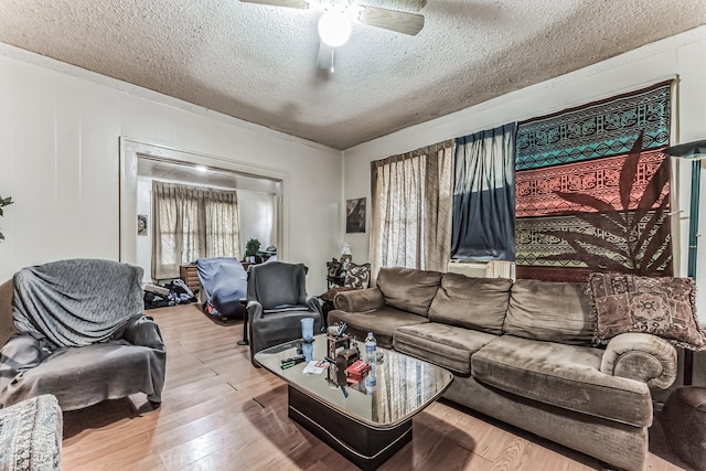 living room featuring hardwood / wood-style flooring, ceiling fan, and a textured ceiling