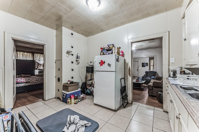 kitchen featuring light tile patterned floors, sink, white cabinets, and white refrigerator