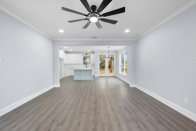 unfurnished living room with wood-type flooring, crown molding, sink, and ceiling fan