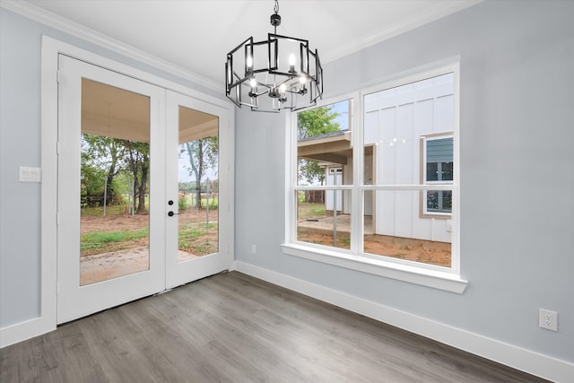 unfurnished dining area featuring french doors, ornamental molding, an inviting chandelier, and hardwood / wood-style floors