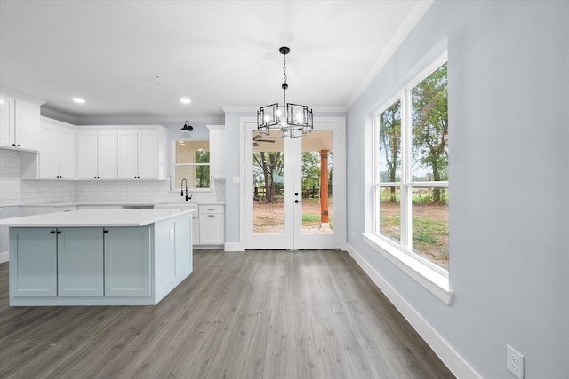 kitchen with a center island, tasteful backsplash, white cabinetry, hanging light fixtures, and hardwood / wood-style floors