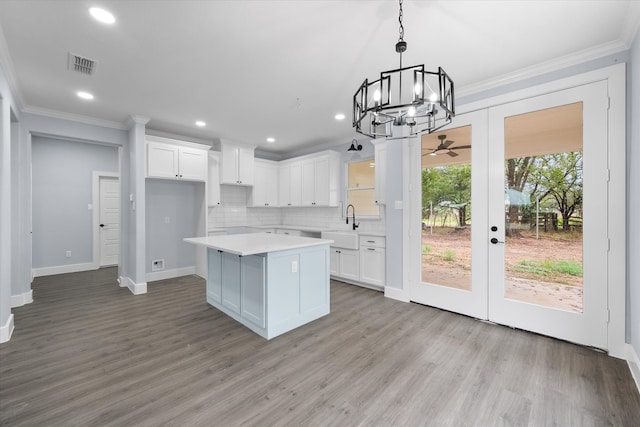 kitchen featuring light hardwood / wood-style floors, a center island, sink, white cabinetry, and hanging light fixtures