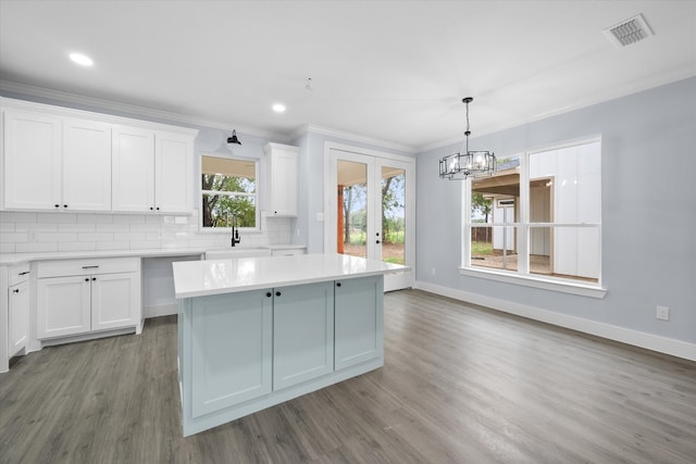 kitchen featuring hardwood / wood-style flooring, decorative light fixtures, a kitchen island, and white cabinets