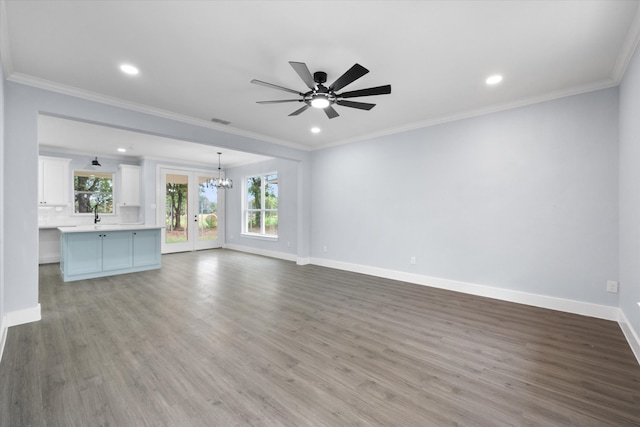 unfurnished living room with ceiling fan with notable chandelier, light hardwood / wood-style flooring, french doors, and crown molding