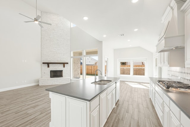 kitchen featuring stainless steel gas stovetop, sink, light hardwood / wood-style flooring, and white cabinets