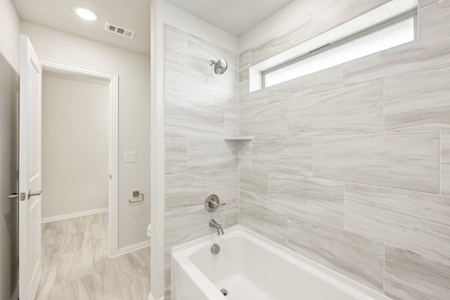 bathroom featuring tiled shower / bath and toilet