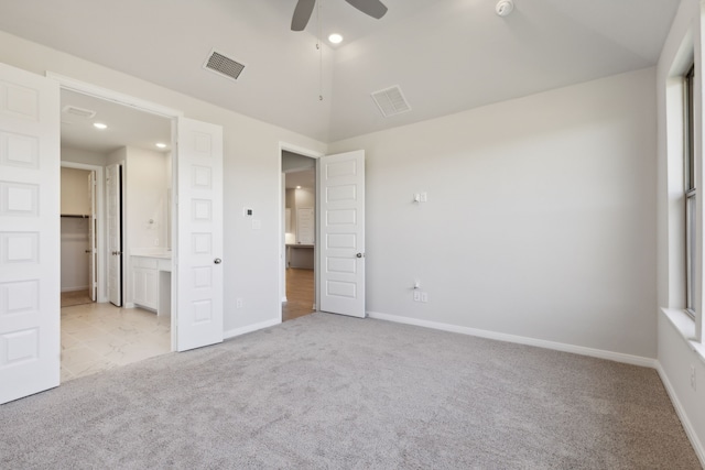 unfurnished bedroom with lofted ceiling, light colored carpet, ceiling fan, and ensuite bathroom