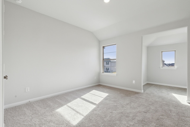 unfurnished room with lofted ceiling, light colored carpet, and a healthy amount of sunlight