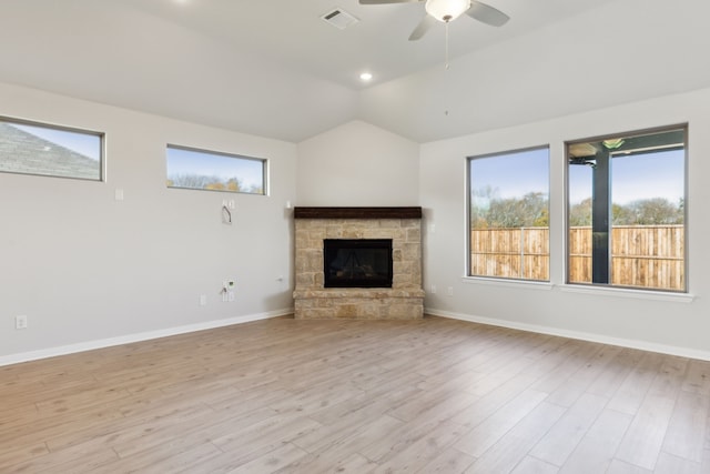 unfurnished living room featuring vaulted ceiling, a stone fireplace, ceiling fan, and light hardwood / wood-style flooring